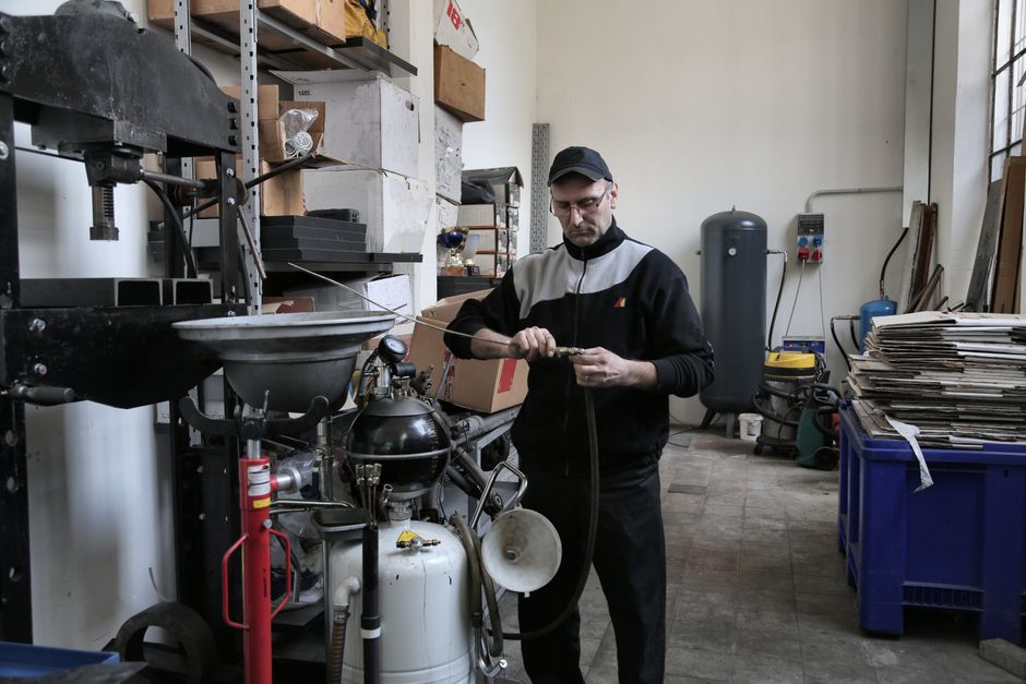 Serious adult mechanic in black uniform fixing compressor tube while working in professional workshop