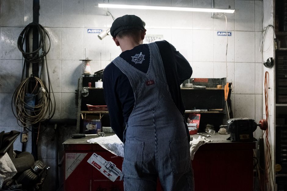 Male auto mechanic working in a garage with repair tools and machinery.